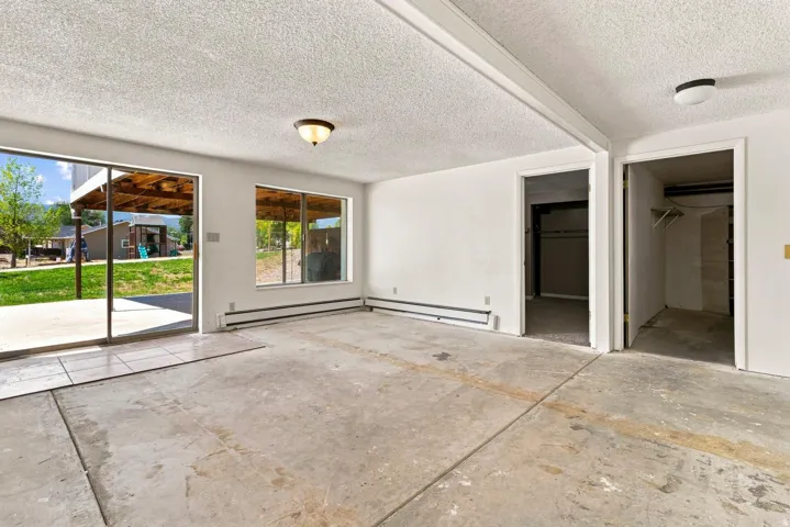 Spacious interior room featuring concrete flooring and textured ceiling