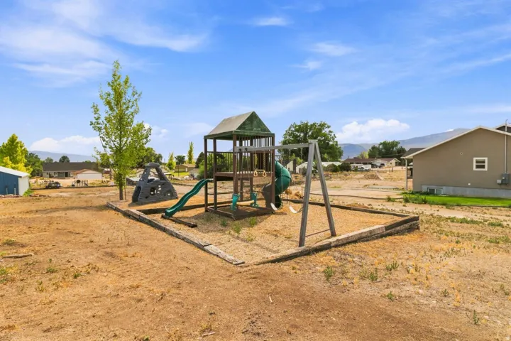 Outdoor play structure featuring a slide, swings, and climbing elements within a contained area