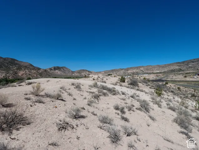 Expansive desert landscape featuring natural scrub brush and distant mountain ranges