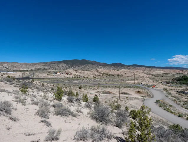 Expansive desert landscape featuring a winding gravel road and distant mountain range
