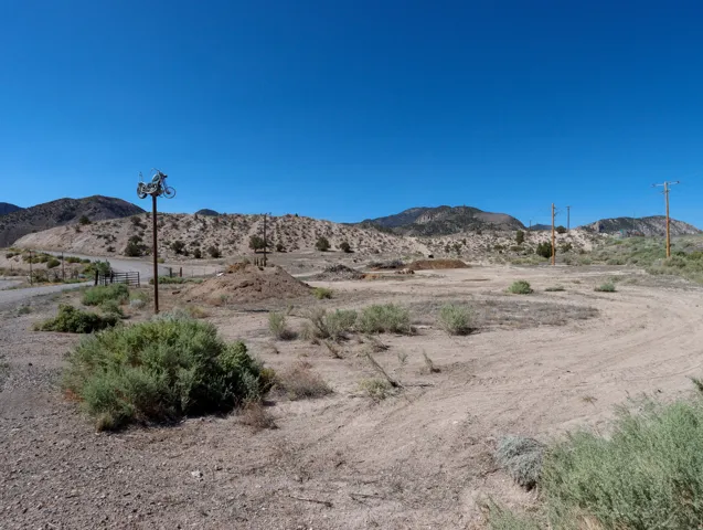 Expansive undeveloped land featuring a dirt track, natural desert landscaping, and distant mountain ranges