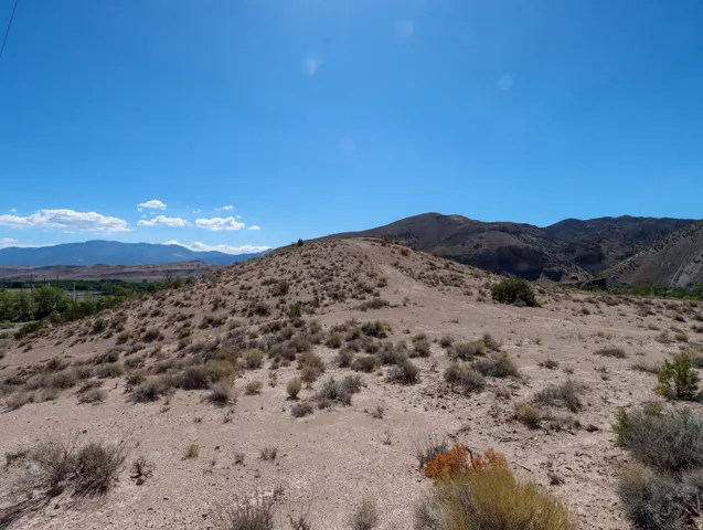 Expansive desert landscape featuring rolling hills and sparse vegetation