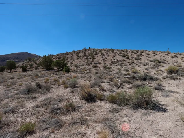 Undeveloped land featuring natural desert vegetation, varied topography, and distant hills under a clear sky