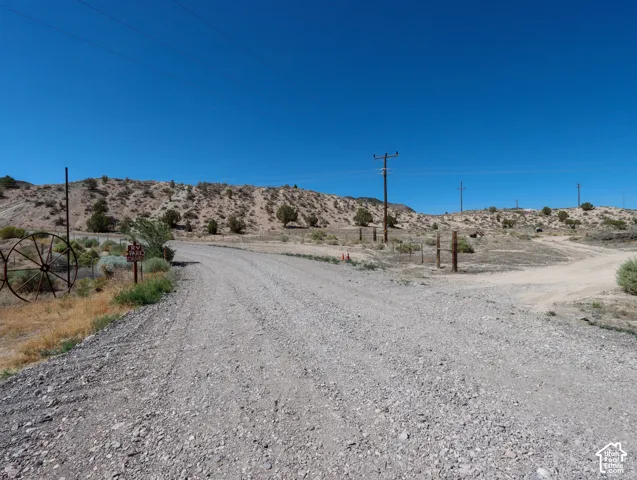 Gravel road winding through undeveloped land featuring desert vegetation and clear blue skies