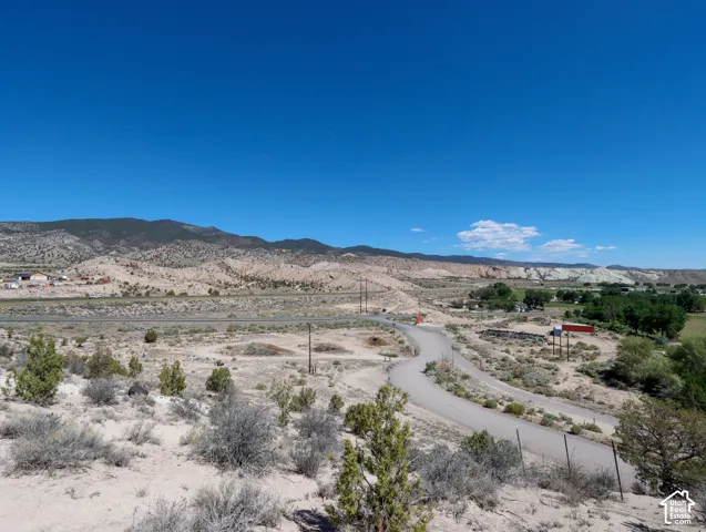Expansive desert landscape featuring a winding dirt road and distant mountain ranges