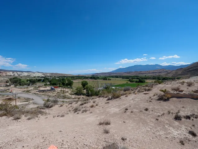 Expansive desert landscape featuring distant mountains and a vibrant green valley
