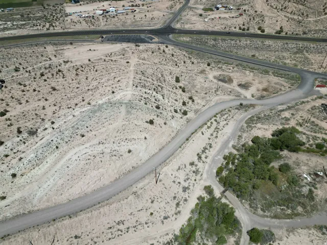 Expansive undeveloped land featuring natural desert vegetation, multiple unpaved roads, and distant paved infrastructure