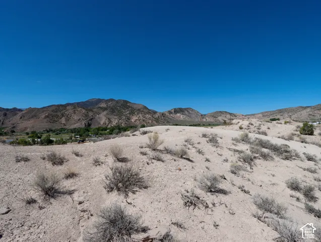 Expansive desert landscape featuring rugged terrain, scattered shrubbery, and distant mountains