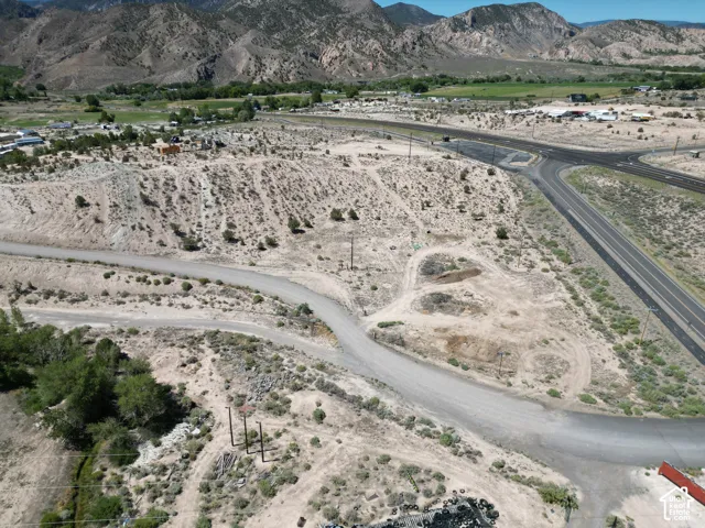 Expansive undeveloped land featuring a gravel road, mountainous backdrop, and established roadways