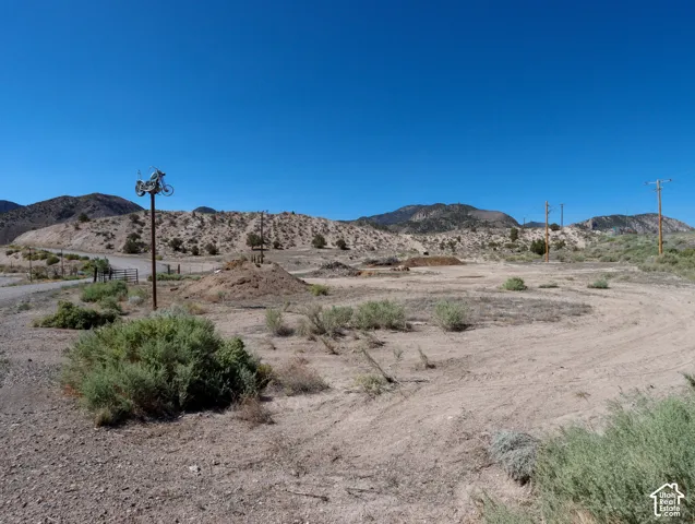 Expansive undeveloped land featuring a dirt track, natural desert landscaping, and distant mountain ranges