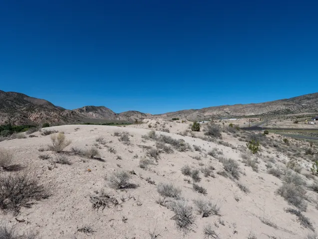 Expansive desert landscape featuring natural scrub brush and distant mountain ranges