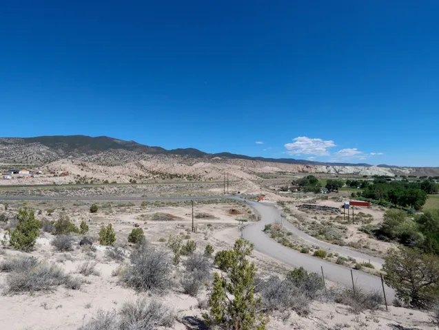 Expansive desert landscape featuring a winding dirt road and distant mountain ranges