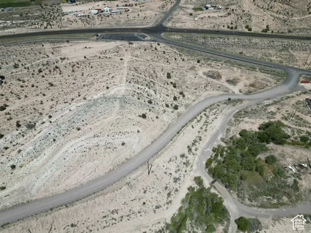 Expansive undeveloped land featuring natural desert vegetation, multiple unpaved roads, and distant paved infrastructure