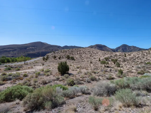 Expansive desert landscape featuring rolling hills and sparse vegetation