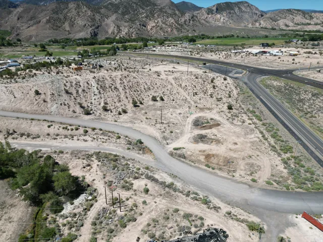 Expansive undeveloped land featuring a gravel road, mountainous backdrop, and established roadways