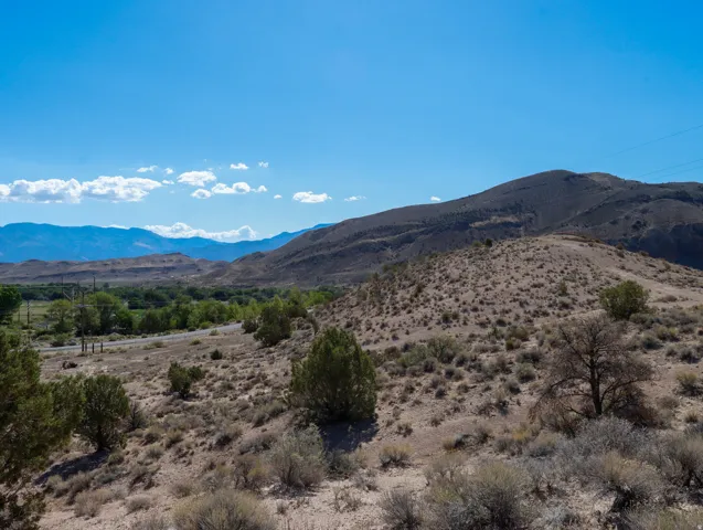 Expansive desert landscape featuring rolling hills and distant mountains under a clear blue sky