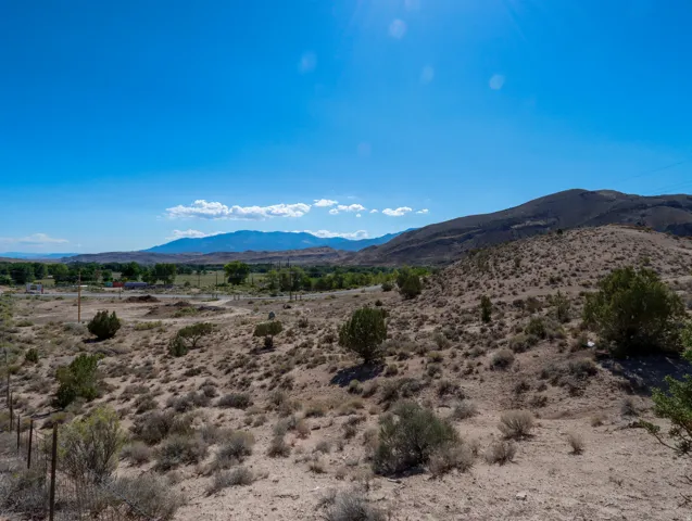 Expansive desert landscape featuring rolling hills and distant mountains under a clear blue sky