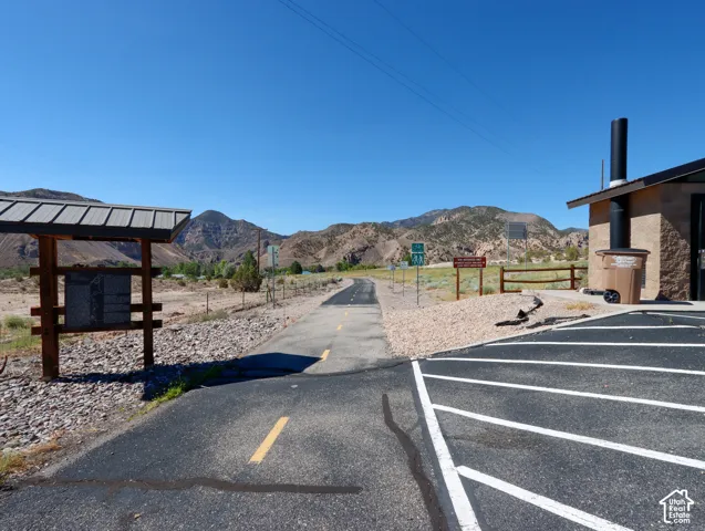 Asphalt parking area with painted lines, a paved path, and a stone-clad building