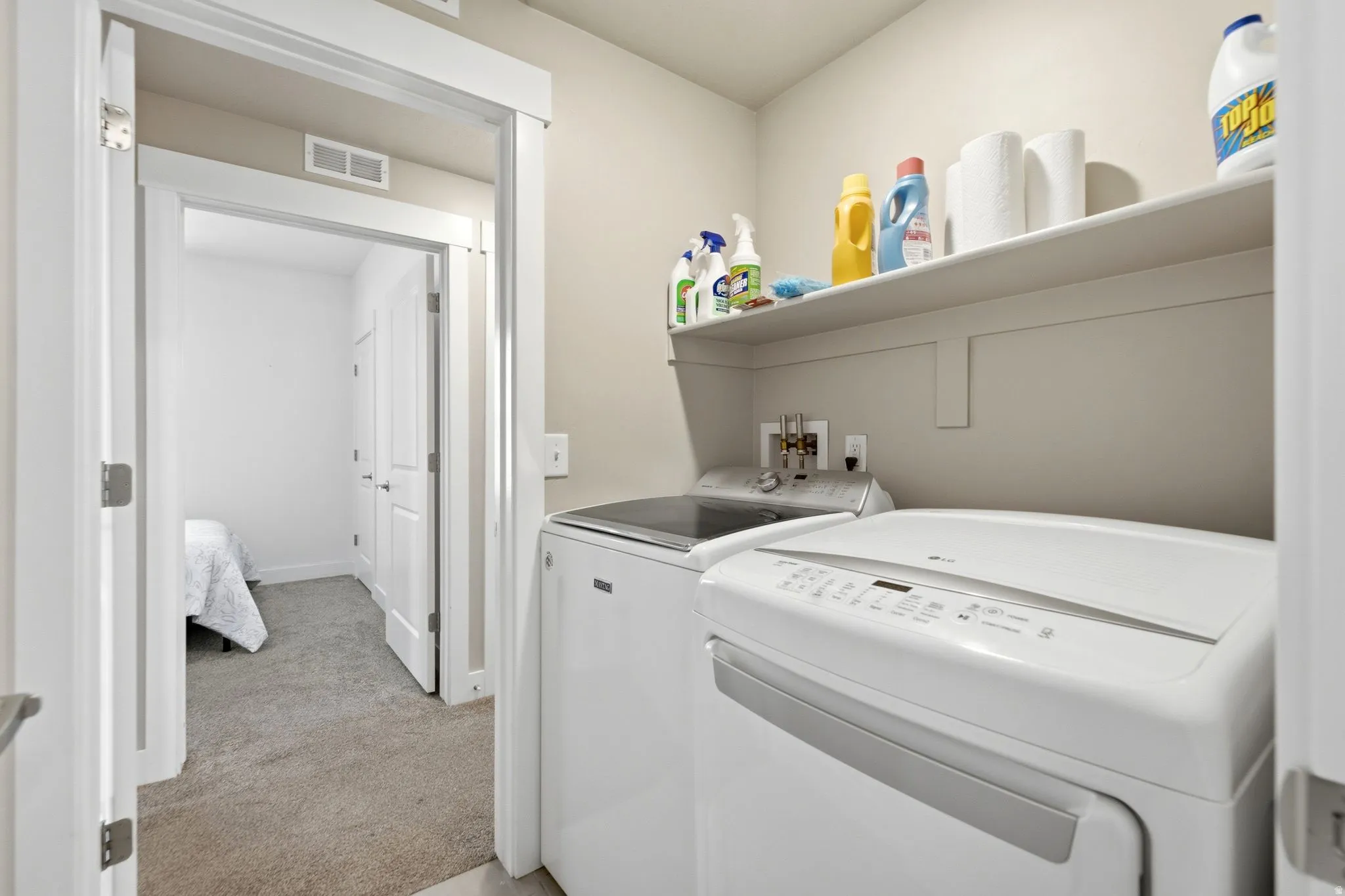 Dedicated laundry area featuring a built-in shelf, neutral wall tones, and overhead ventilation