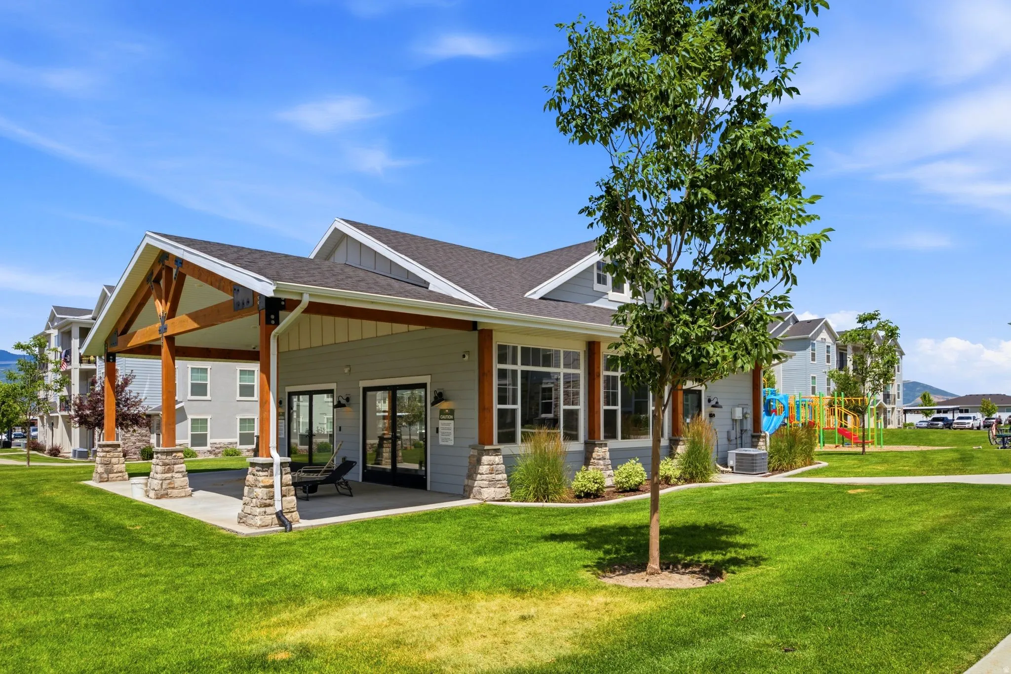 Community building featuring an expansive covered patio with wood beam accents and stone-wrapped columns
