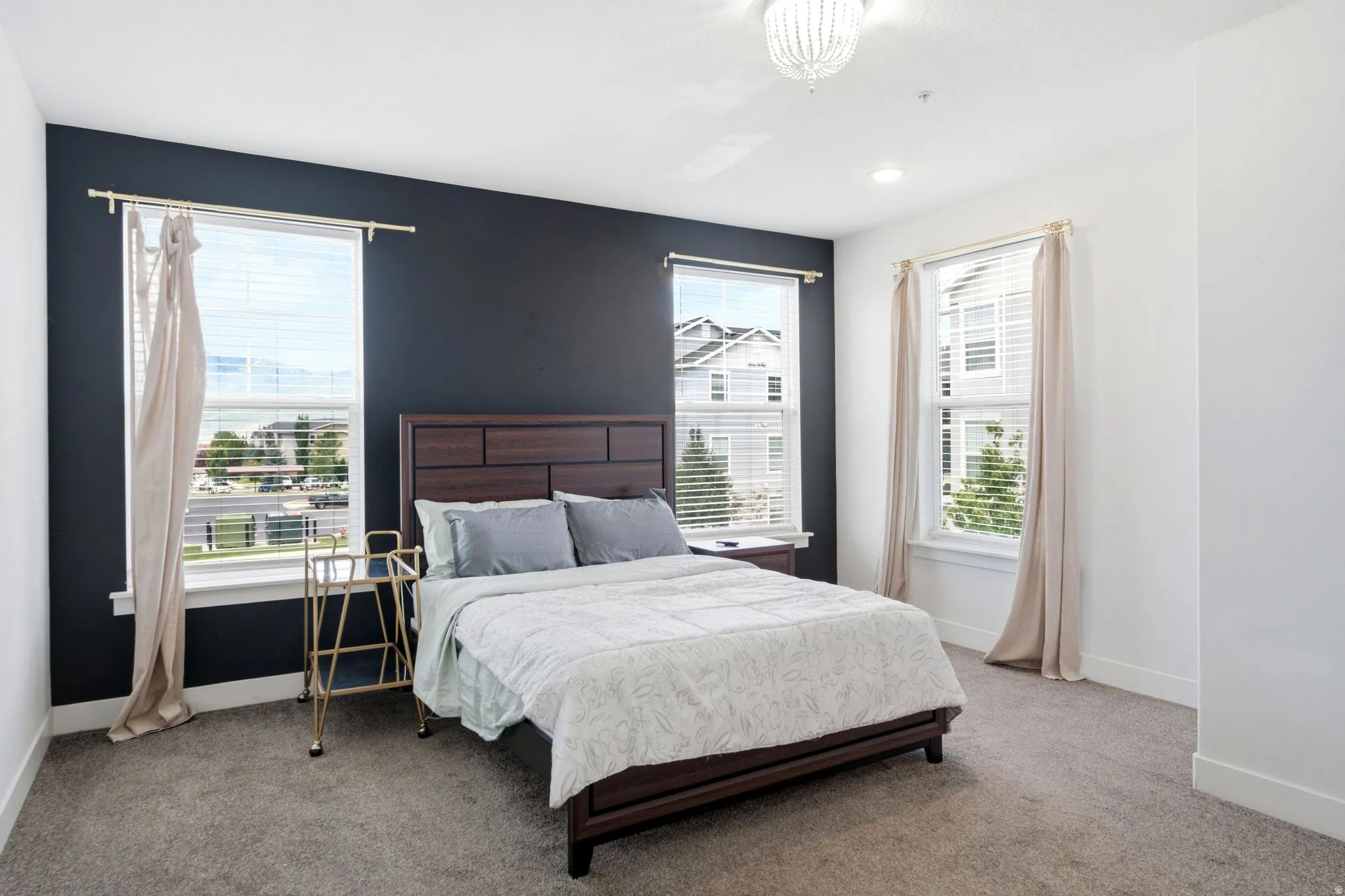 Spacious bedroom featuring dark accent wall, recessed lighting, ceiling light fixture, and two large windows with blinds