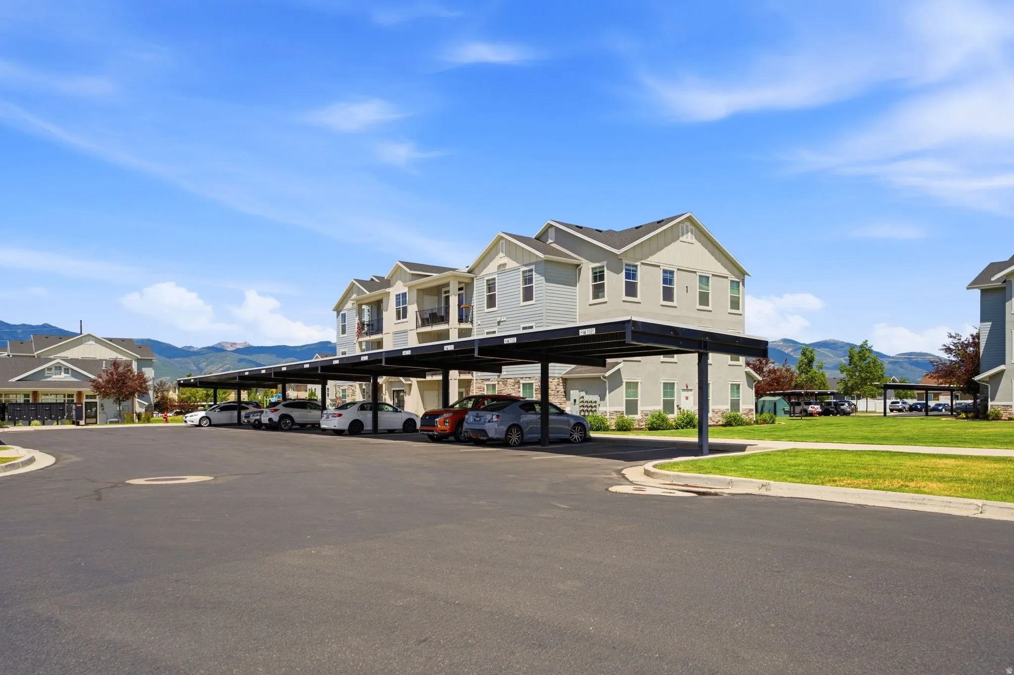 Carport parking structures with an asphalt lot, surrounded by multi-story residential buildings featuring balconies