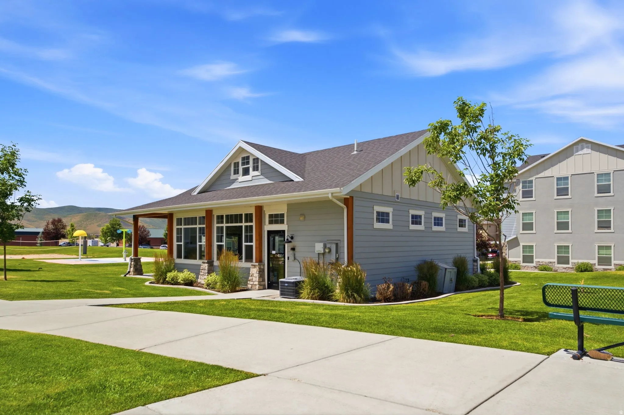 Contemporary clubhouse with an expansive covered porch, stone accents, and large windows