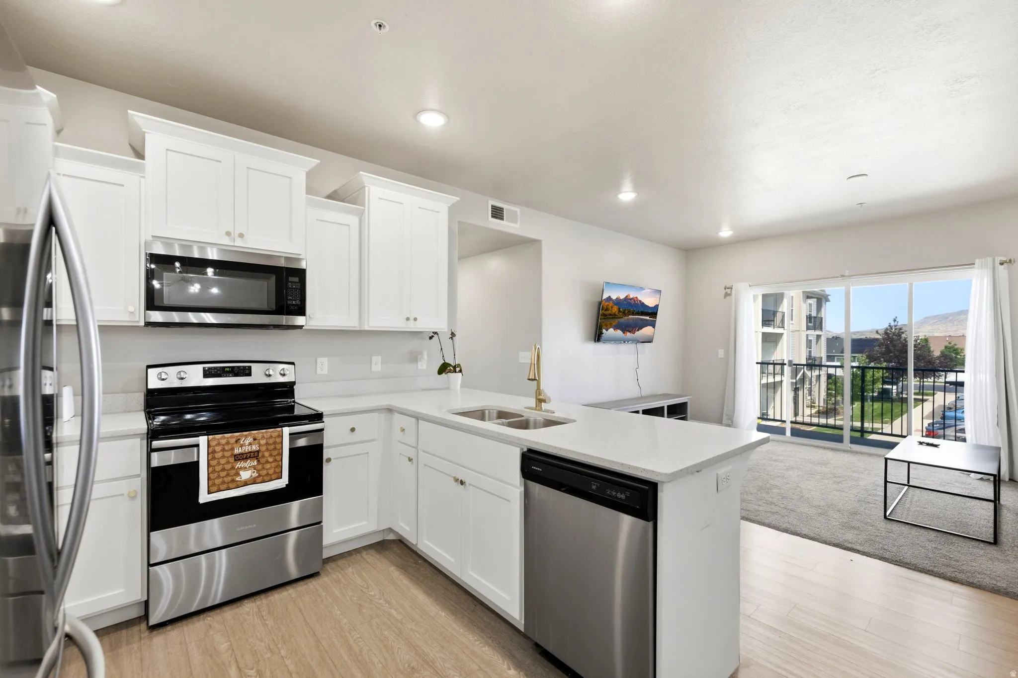 Contemporary kitchen featuring white cabinetry, stainless steel appliances, light countertops, wood-finish flooring, and recessed lighting