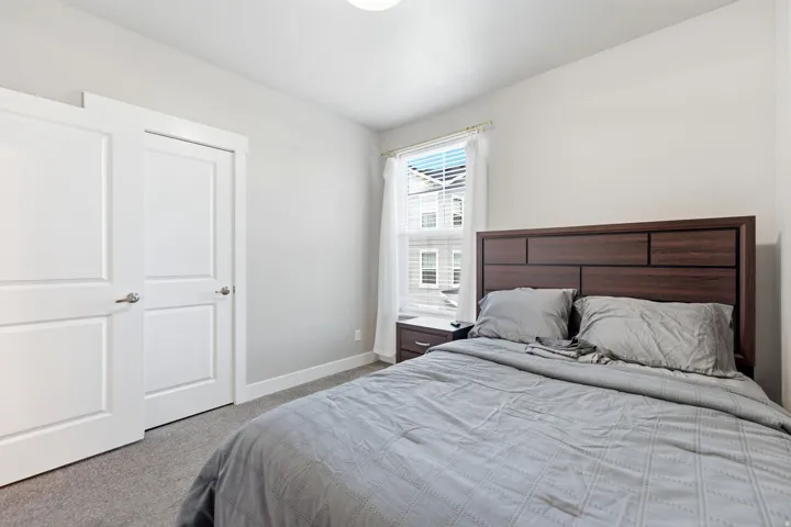 Bedroom featuring soft gray carpeting, white painted walls, and a window with blinds