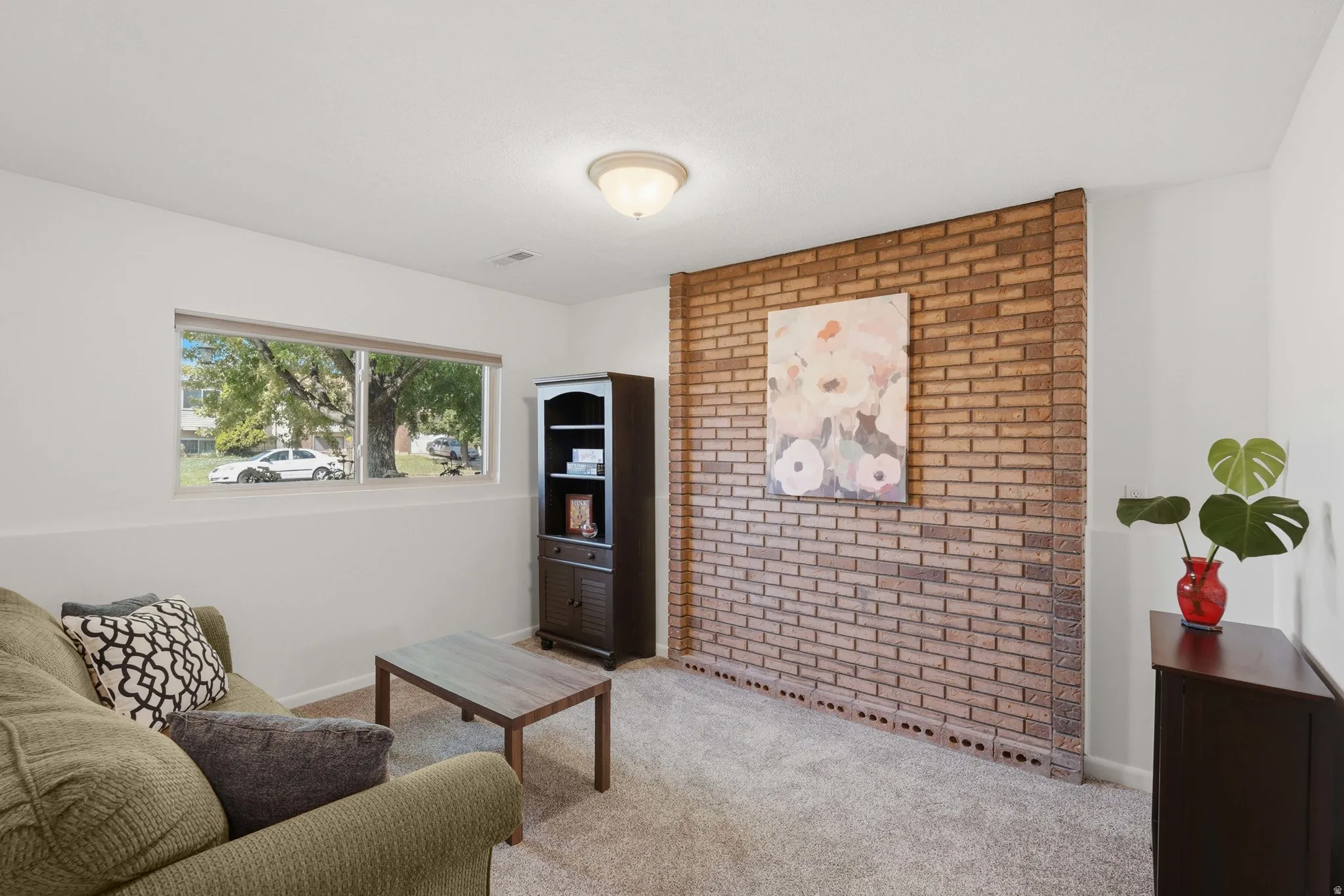 Recessed window featuring exterior views, textured brick accent wall, and neutral carpeting