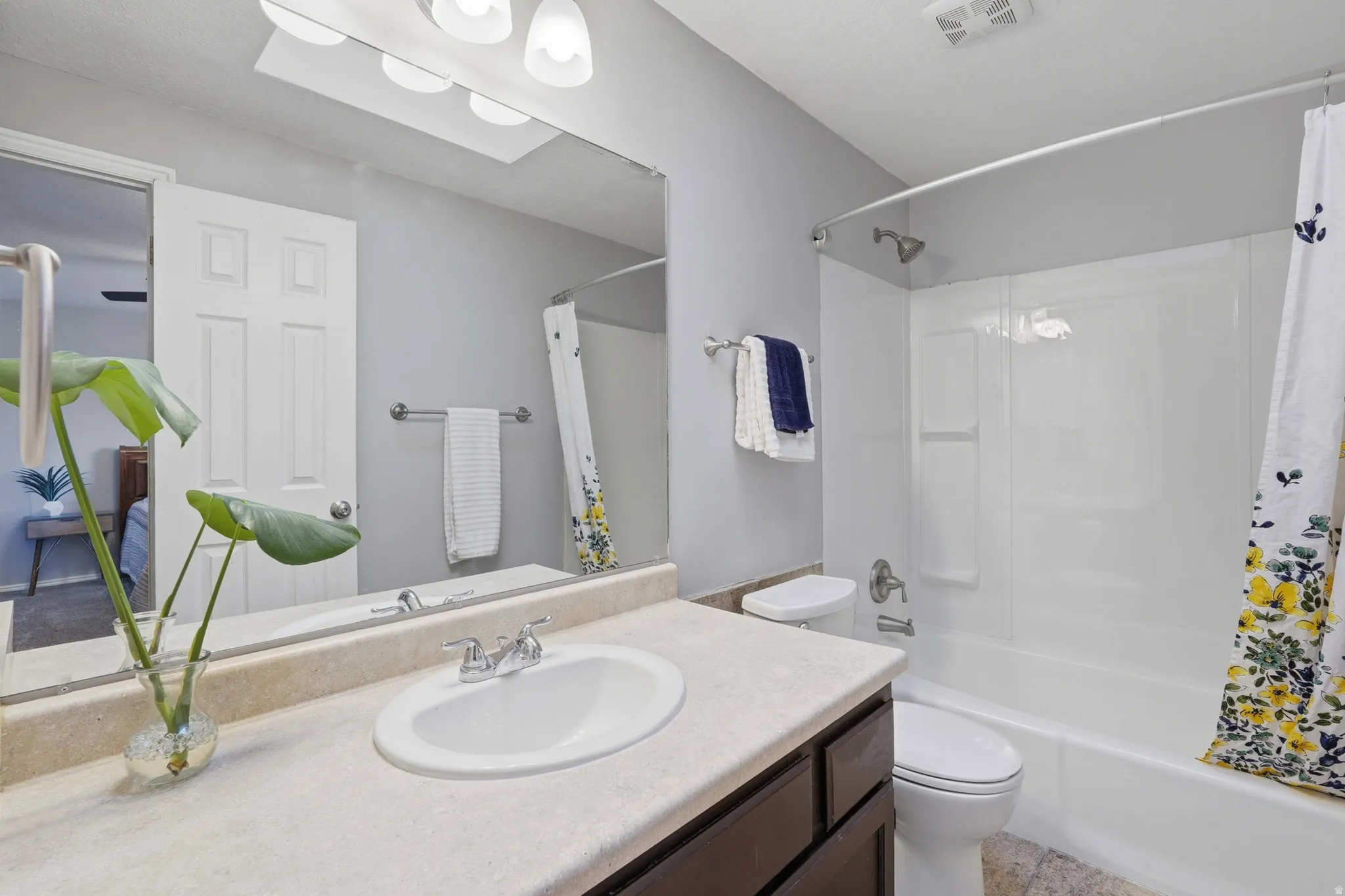 Bathroom featuring a white integrated sink, light-colored countertop, and dark wood-finish cabinetry