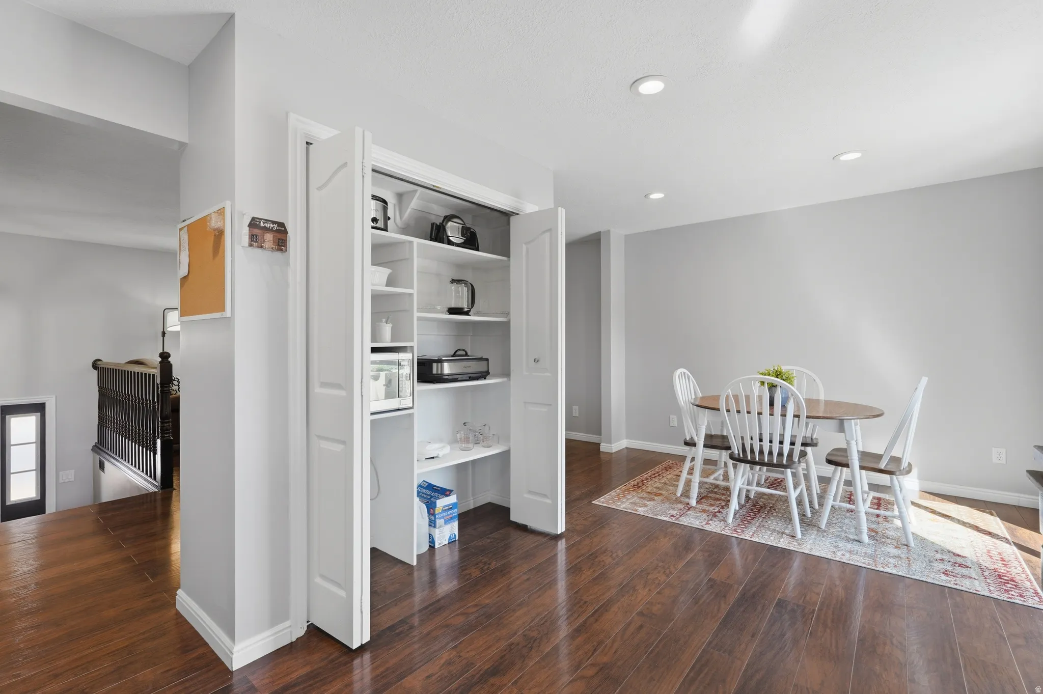 Built-in pantry storage with bi-fold doors, wood-finish flooring, recessed lighting, and a neutral wall palette