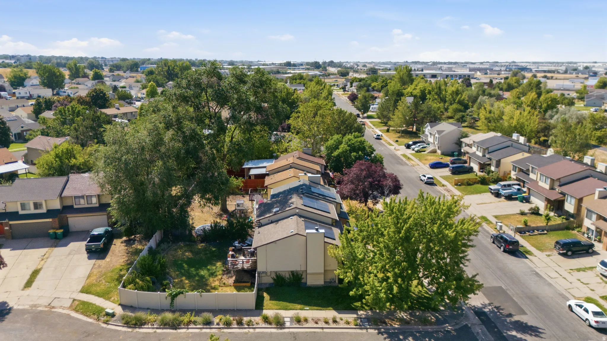 Suburban street featuring mature trees and a mix of single-family homes and townhomes with various rooflines