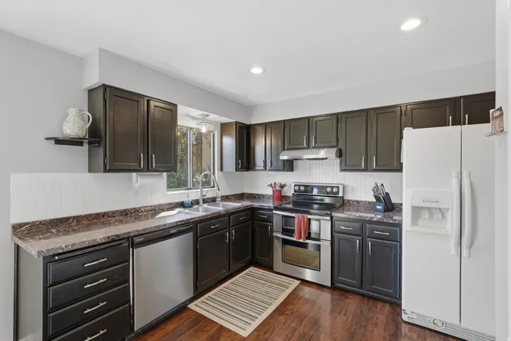 Kitchen featuring wood-finish flooring, dark cabinetry, and mottled countertops