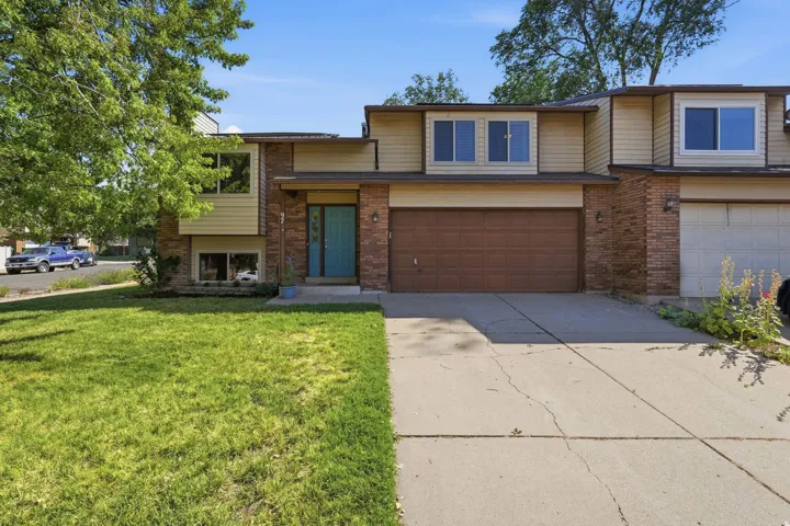Split-level residence featuring brick and siding facade, a prominent turquoise entry door, and an integrated garage