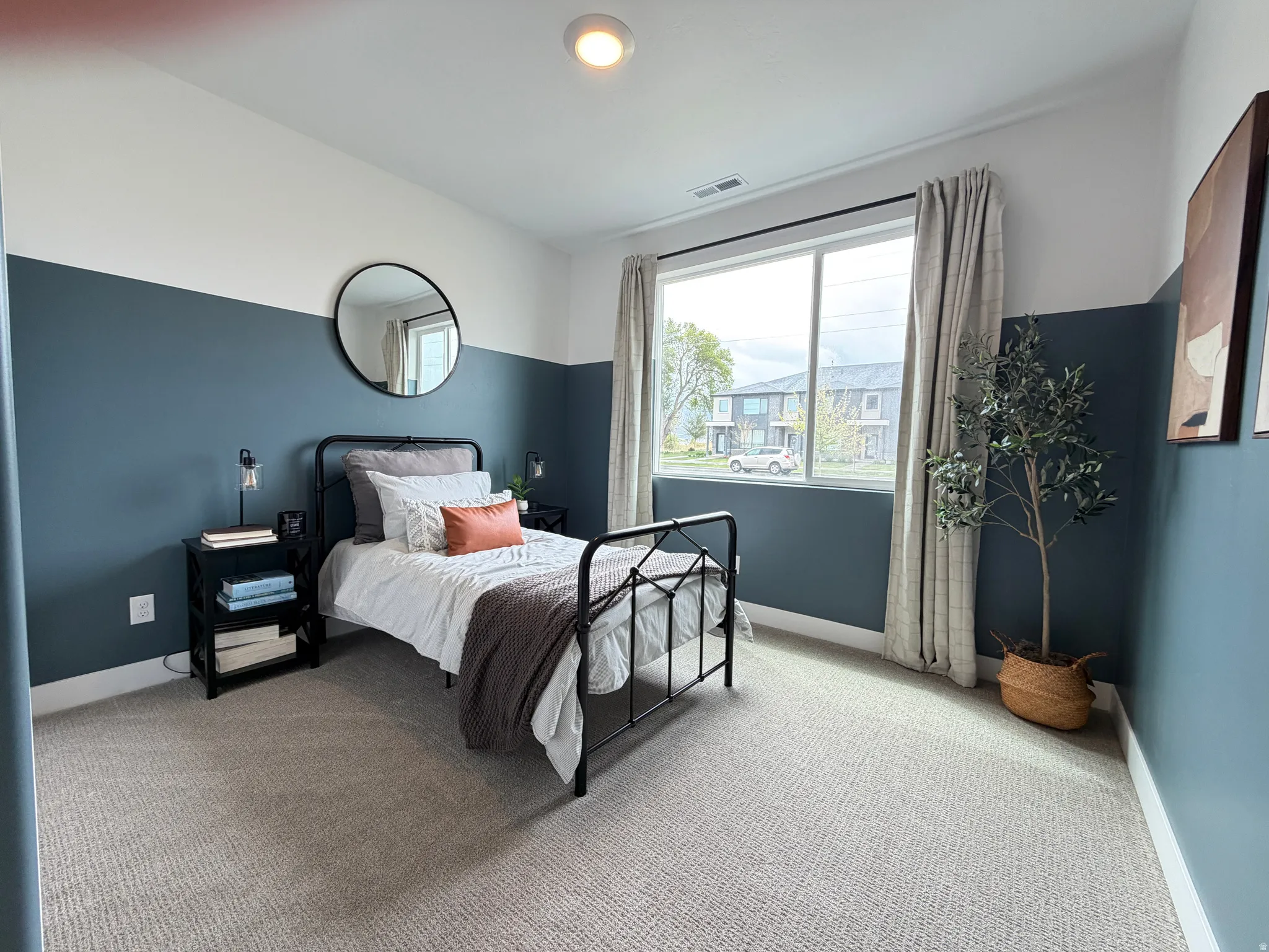 Spacious room with a large window, textured carpeting, and a two-tone wall treatment