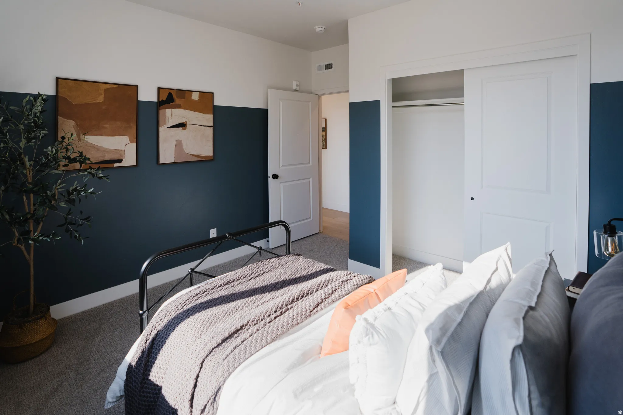 Carpeted bedroom featuring a two-tone wall design, a built-in closet with sliding doors, and a solid core door