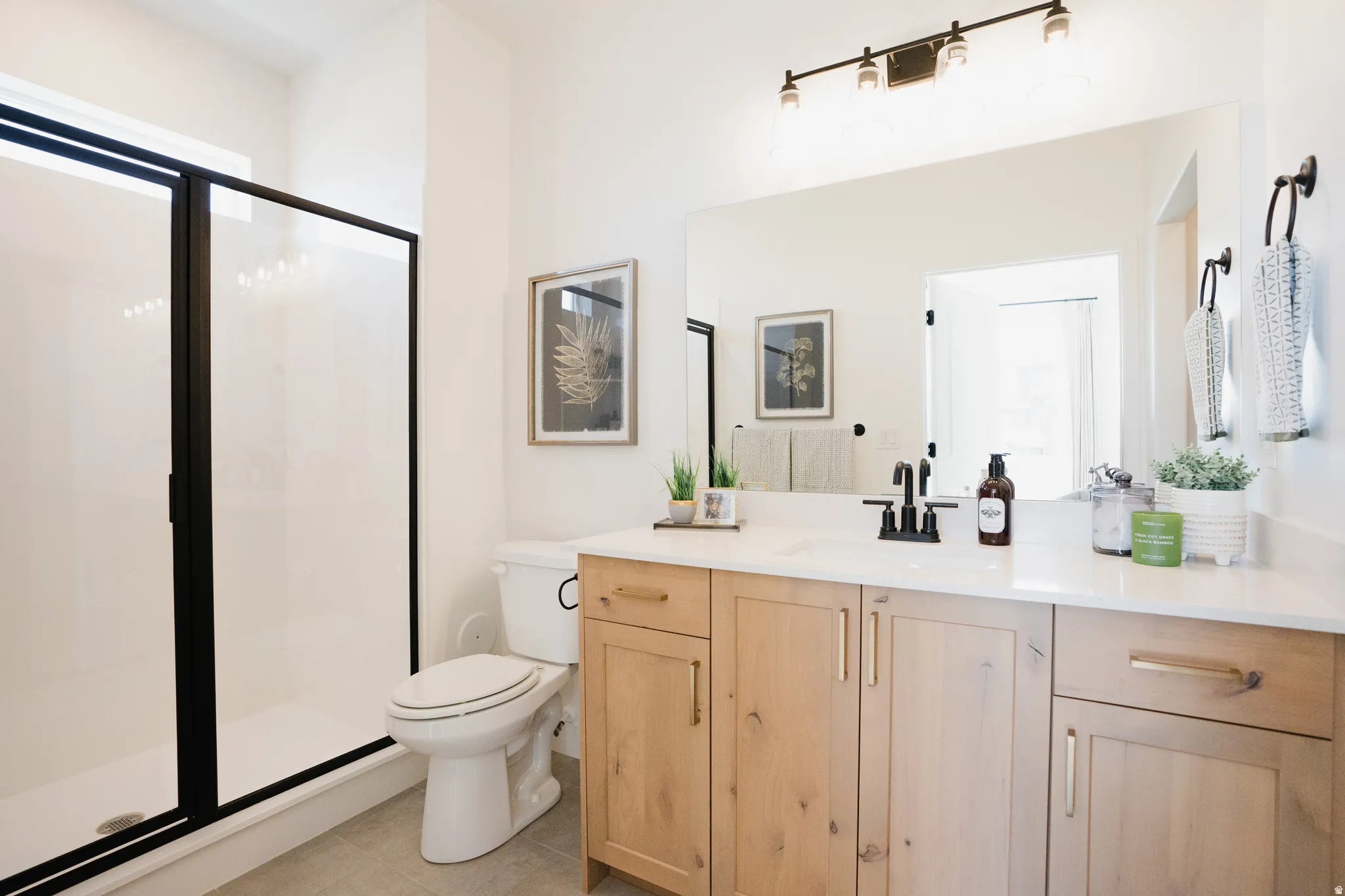 Bathroom featuring a light wood-finish vanity with a white countertop, a large mirror, and a track lighting fixture