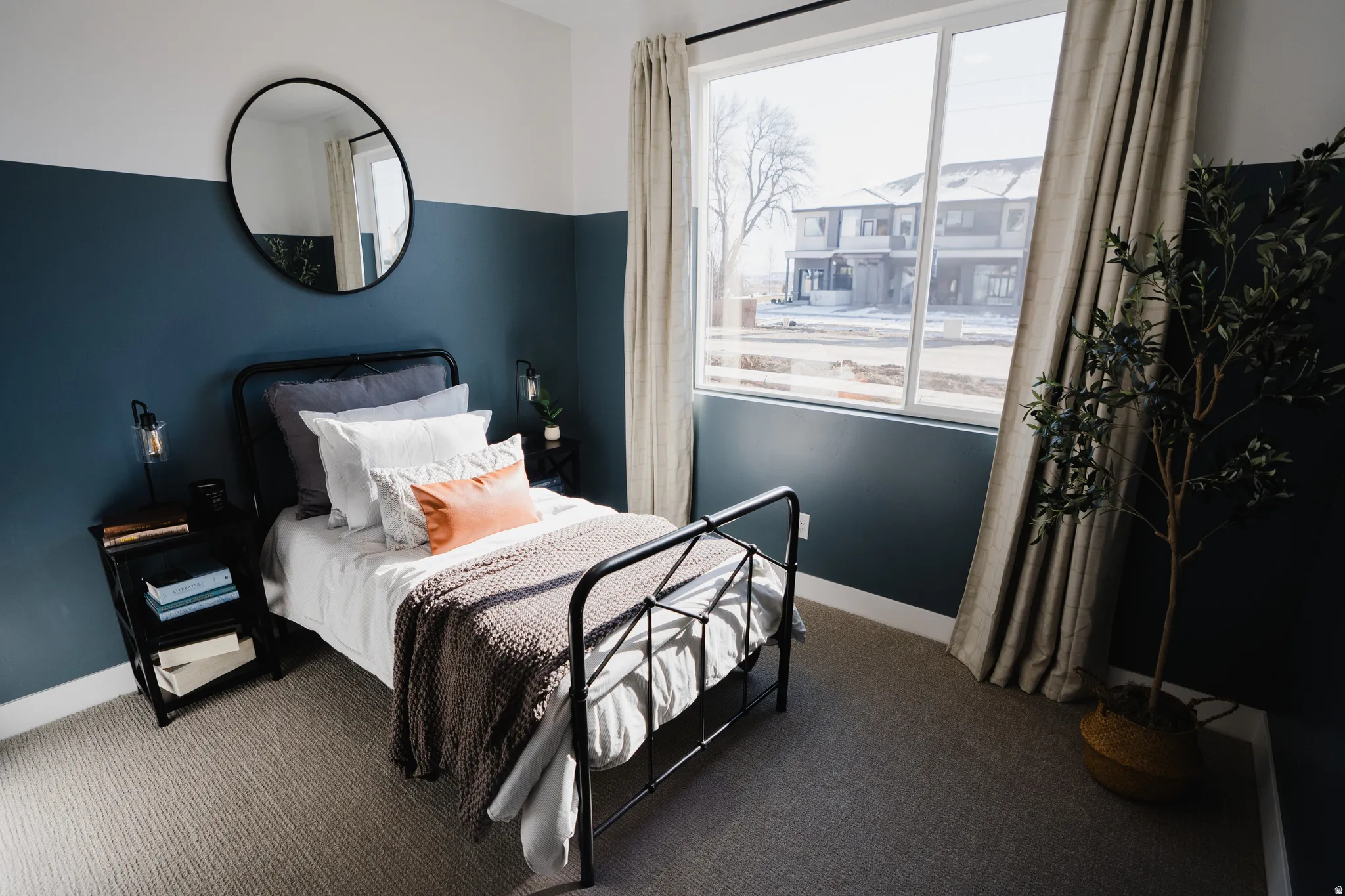 Carpeted room featuring a large window, white trim, and a two-tone painted wall with a circular mirror