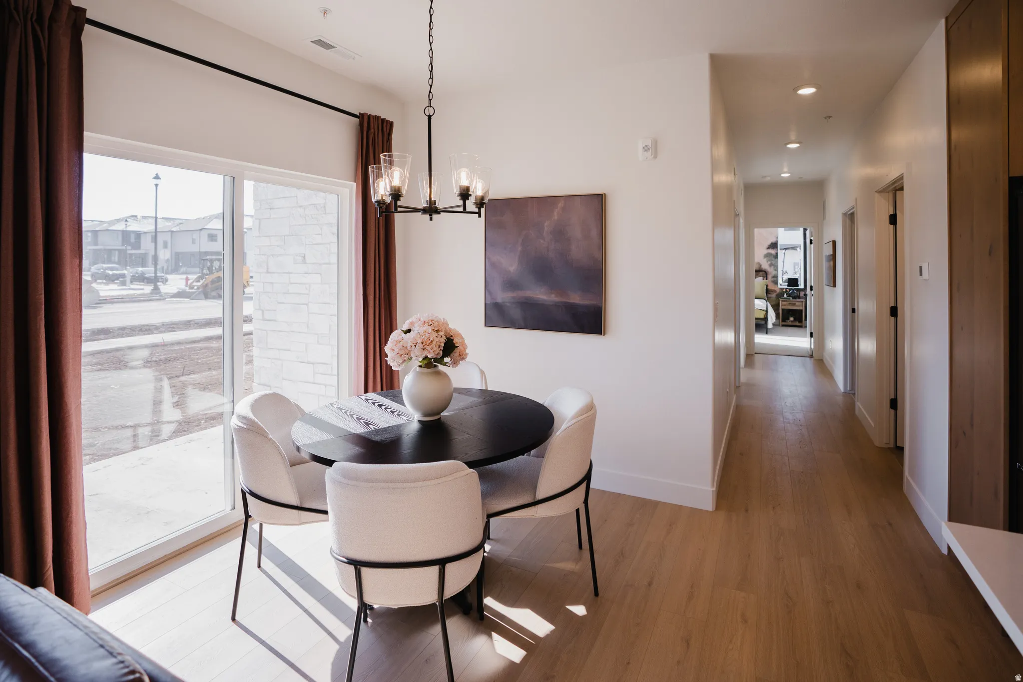 Dining area with light wood-finish flooring, a contemporary black chandelier, and a sliding glass door