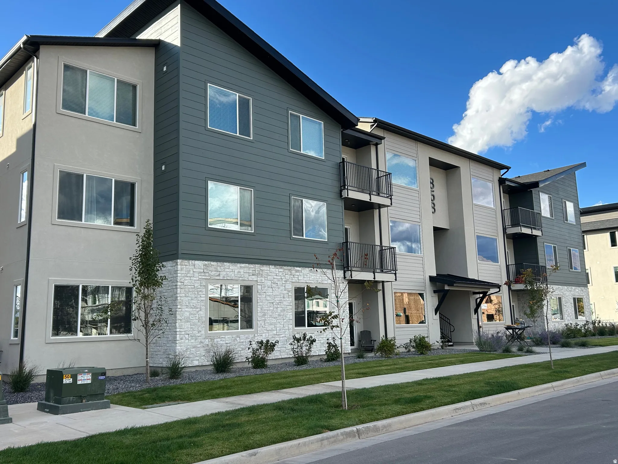 Contemporary multi-story building featuring a facade of horizontal siding, stucco, and stone veneer accents