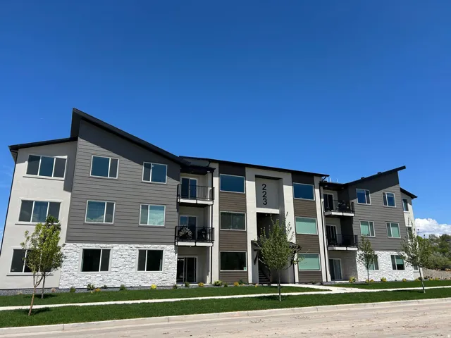 Contemporary facade with a multi-level design featuring horizontal siding, light stucco, and a white stone veneer base