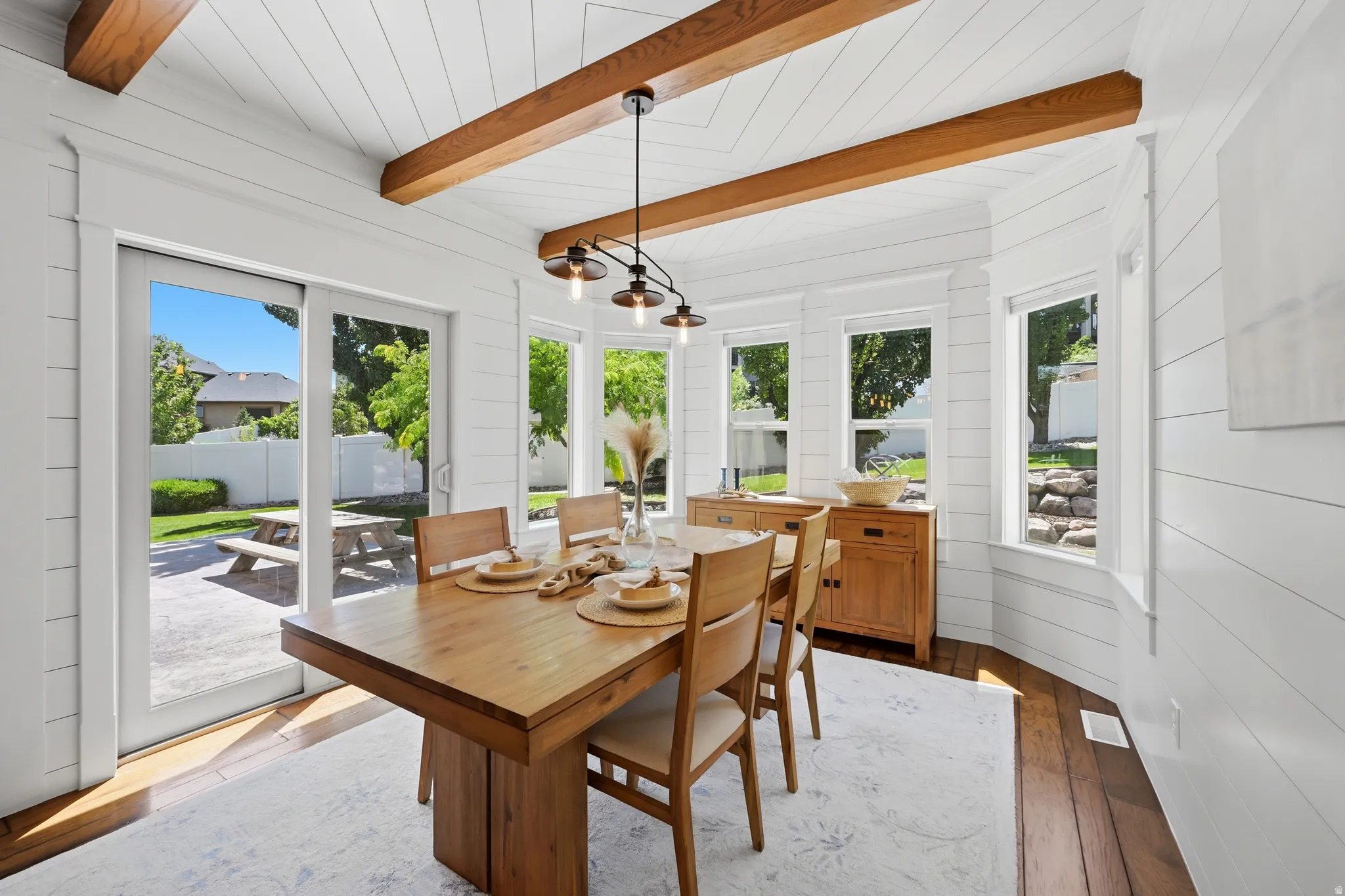 Dining area featuring white shiplap walls, exposed wood ceiling beams, and hard surface wood-finish flooring