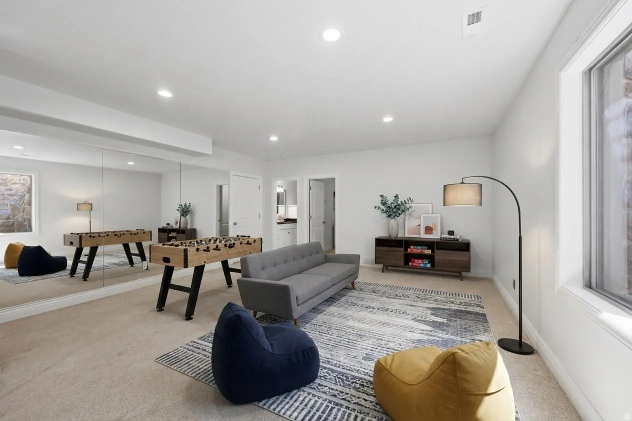 Spacious recreation room featuring wall-to-wall mirrors, recessed lighting, and a neutral carpet