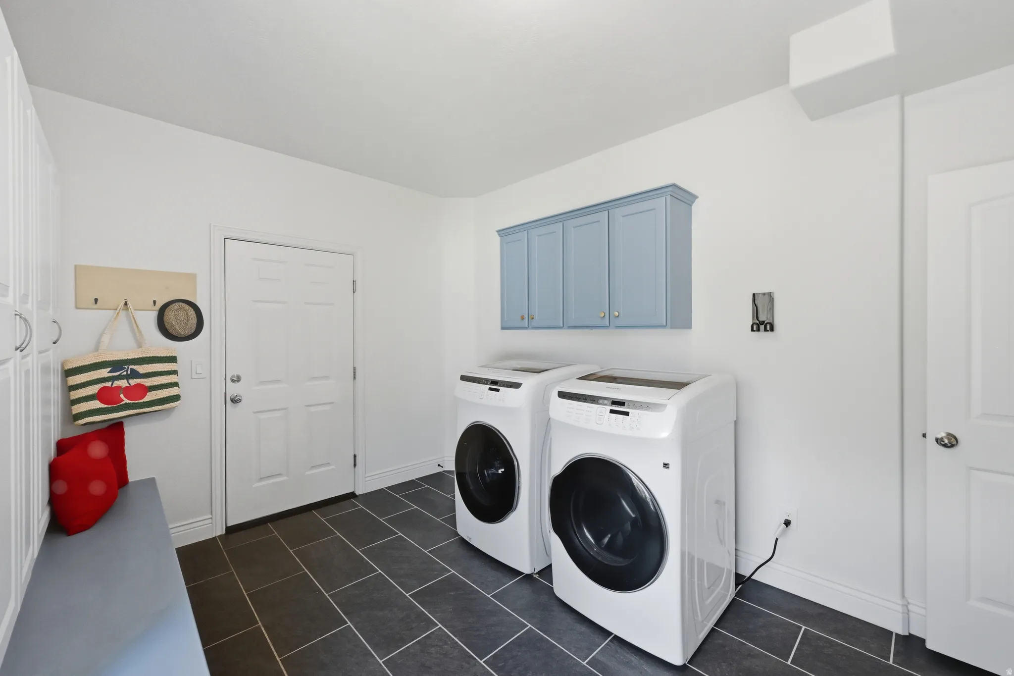 Dedicated laundry space featuring dark rectangular floor tiles
