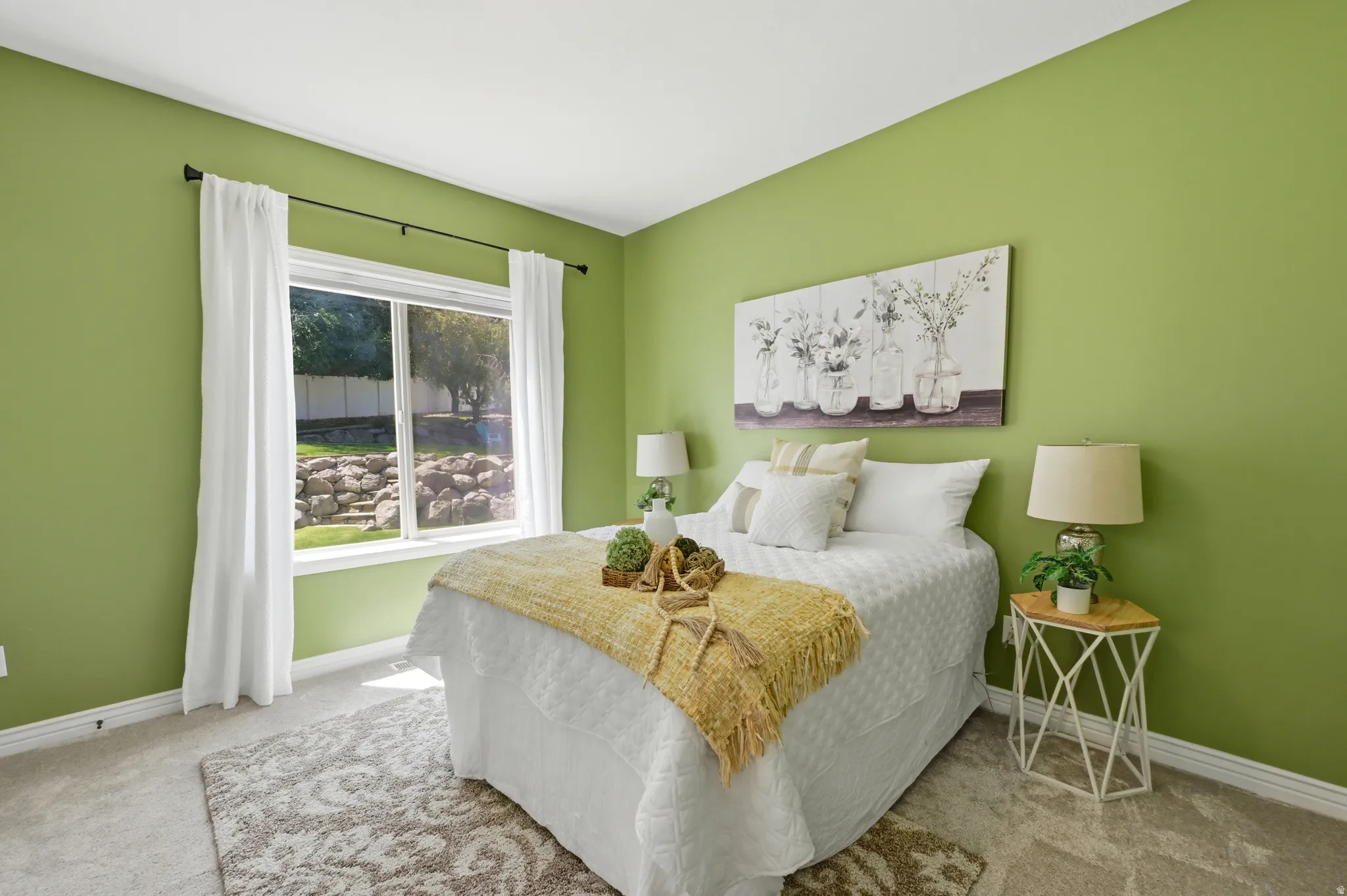 Bedroom featuring a large window, light green walls, white trim, and light-colored carpet