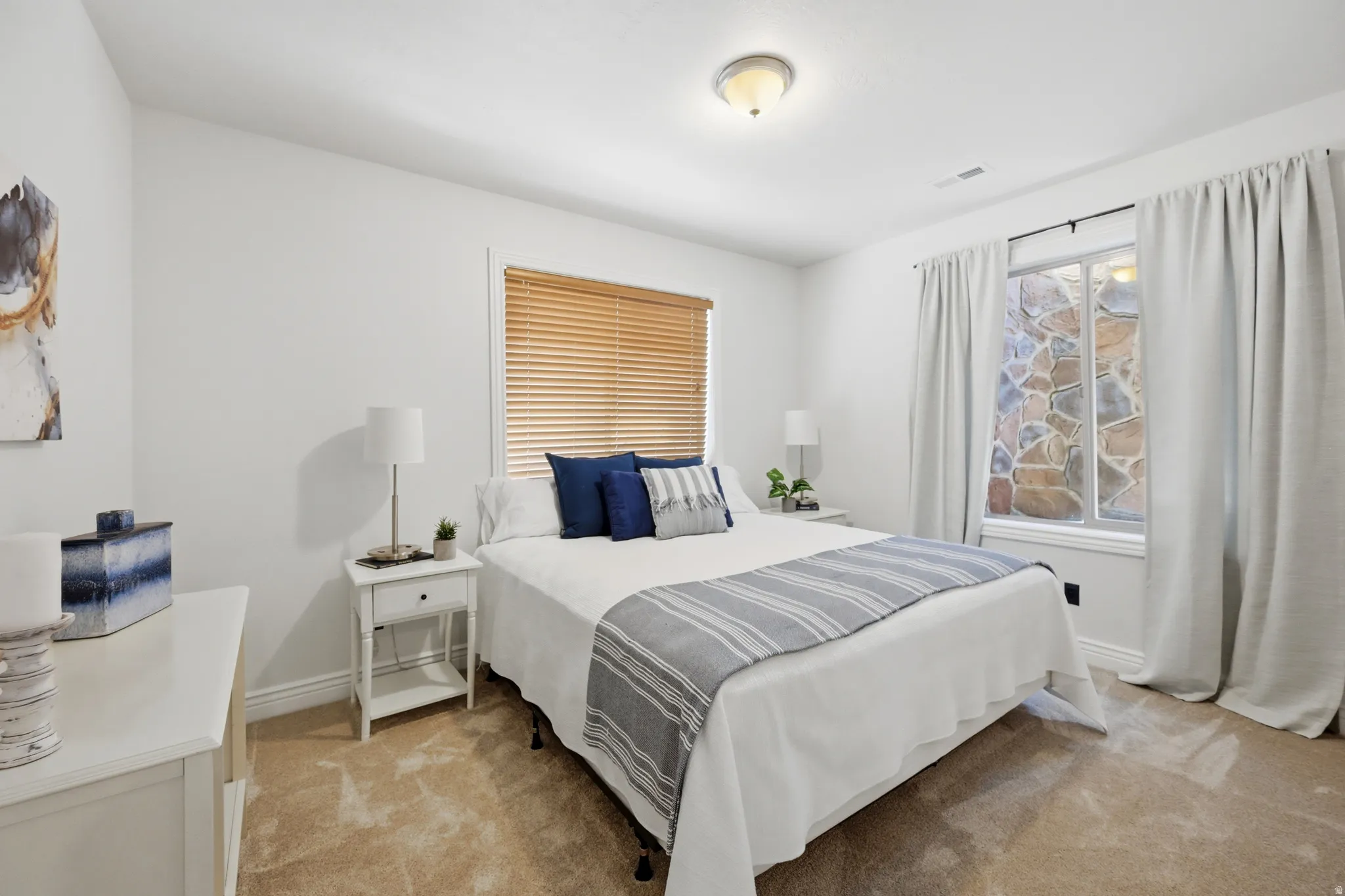 Neutral wall colors with carpeted flooring, featuring a window with wood-finish blinds and a recessed window with stone detailing