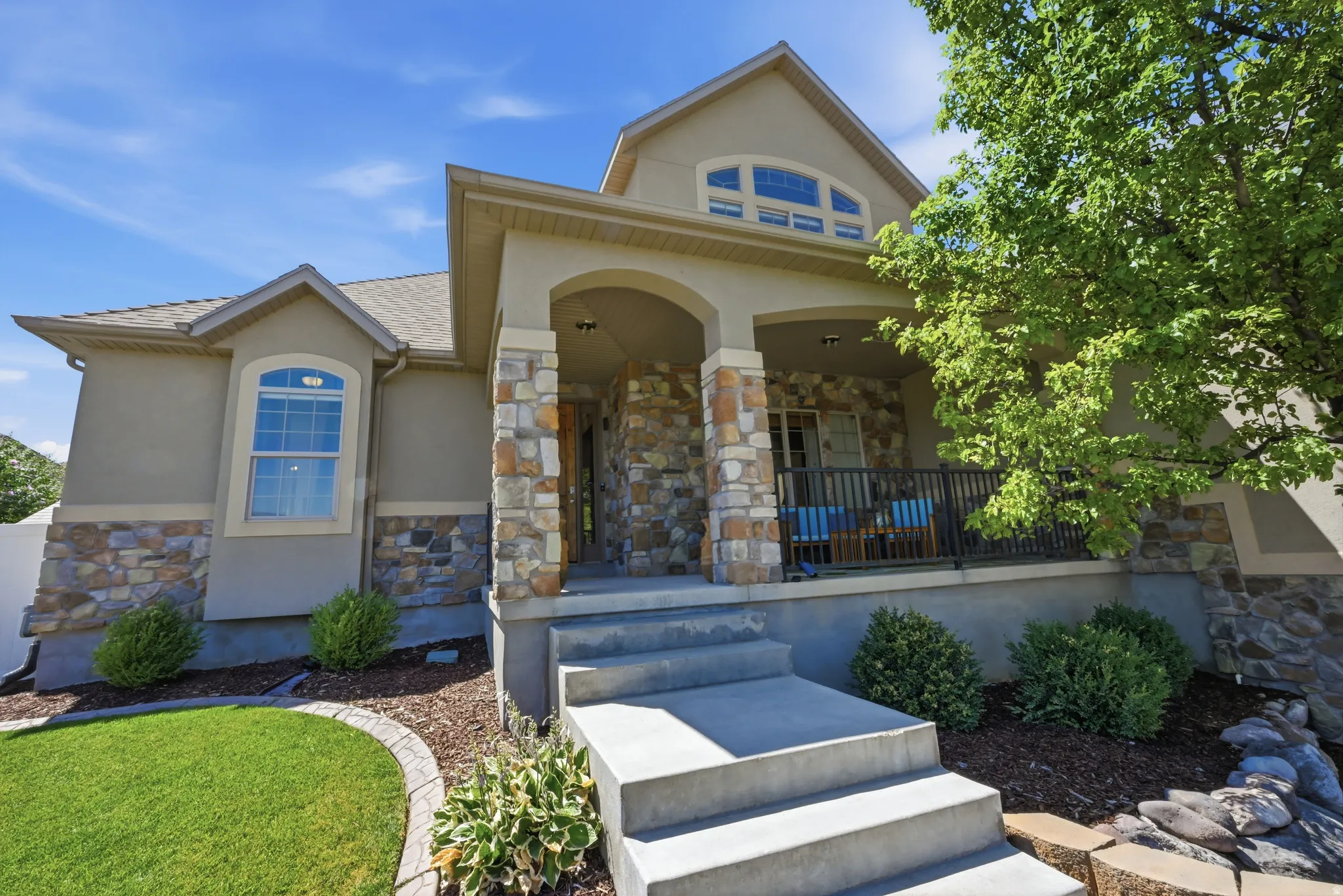 Exterior facade featuring a covered porch, stone accents, and stucco finish