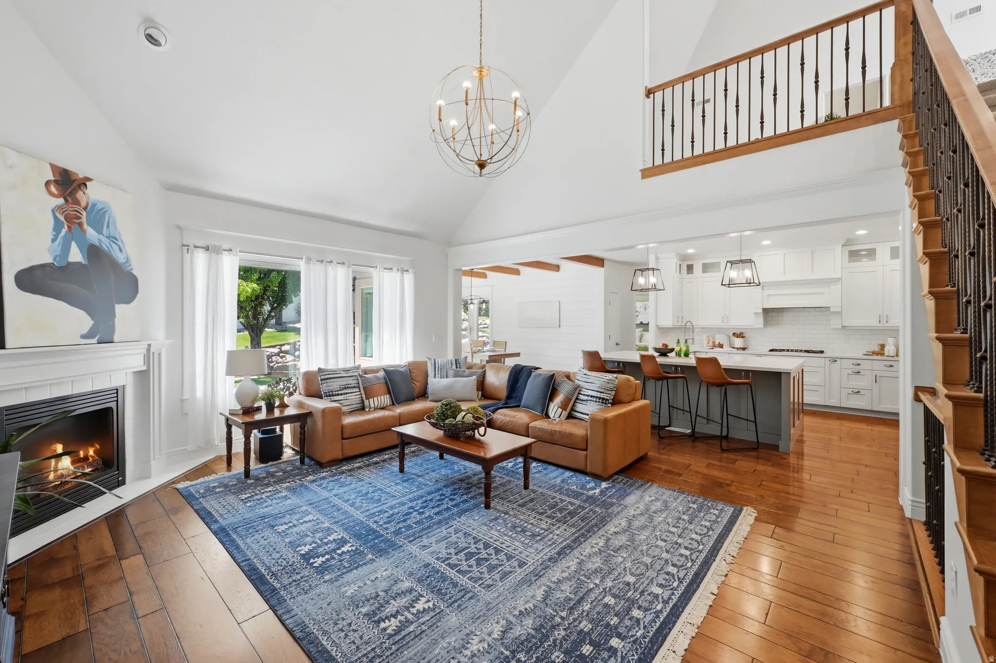 Vaulted living area featuring a fireplace with a white mantel, wood-finish flooring, and ample natural light from multiple windows