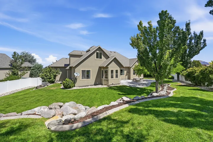Expansive backyard featuring a manicured lawn, established landscaping, and a concrete patio
